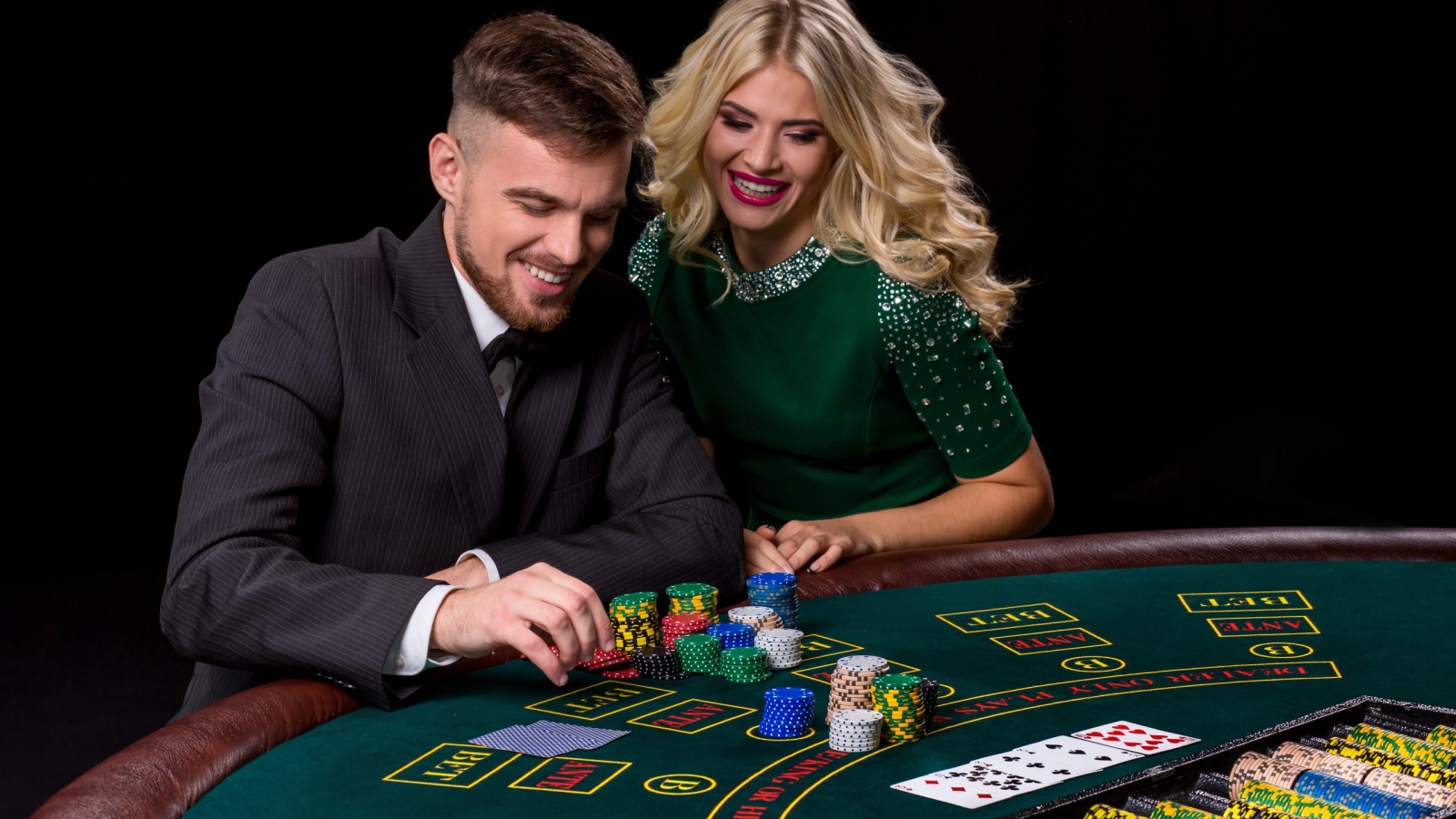 View of young, confident, man with the lady while he's playing poker game. Man bets in poker