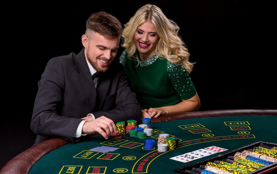 View of young, confident, man with the lady while he's playing poker game. Man bets in poker